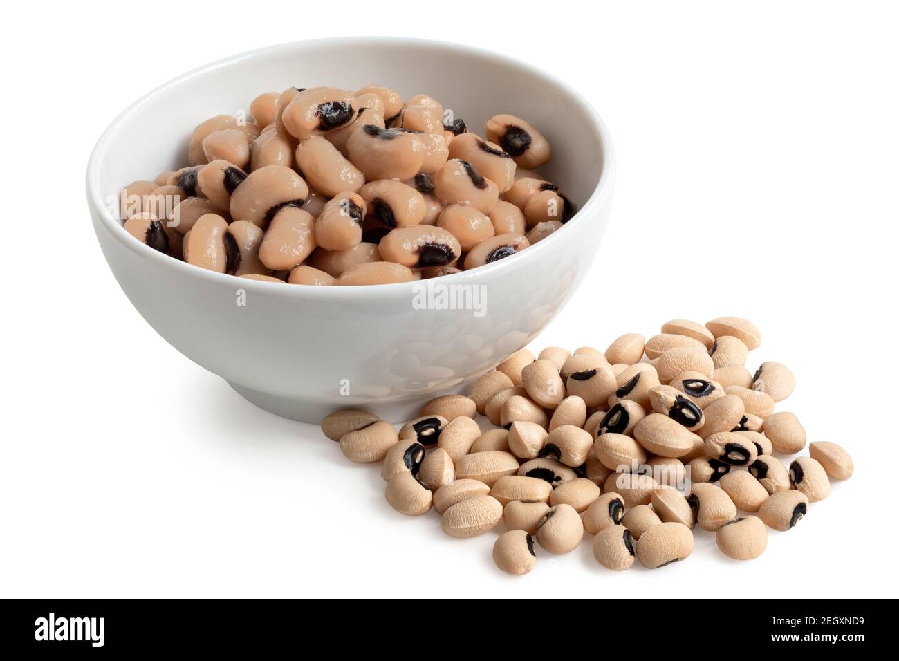 Cooked black-eyed beans in a white ceramic bowl next to uncooked black-eyed beans isolated on white. Stock Photo