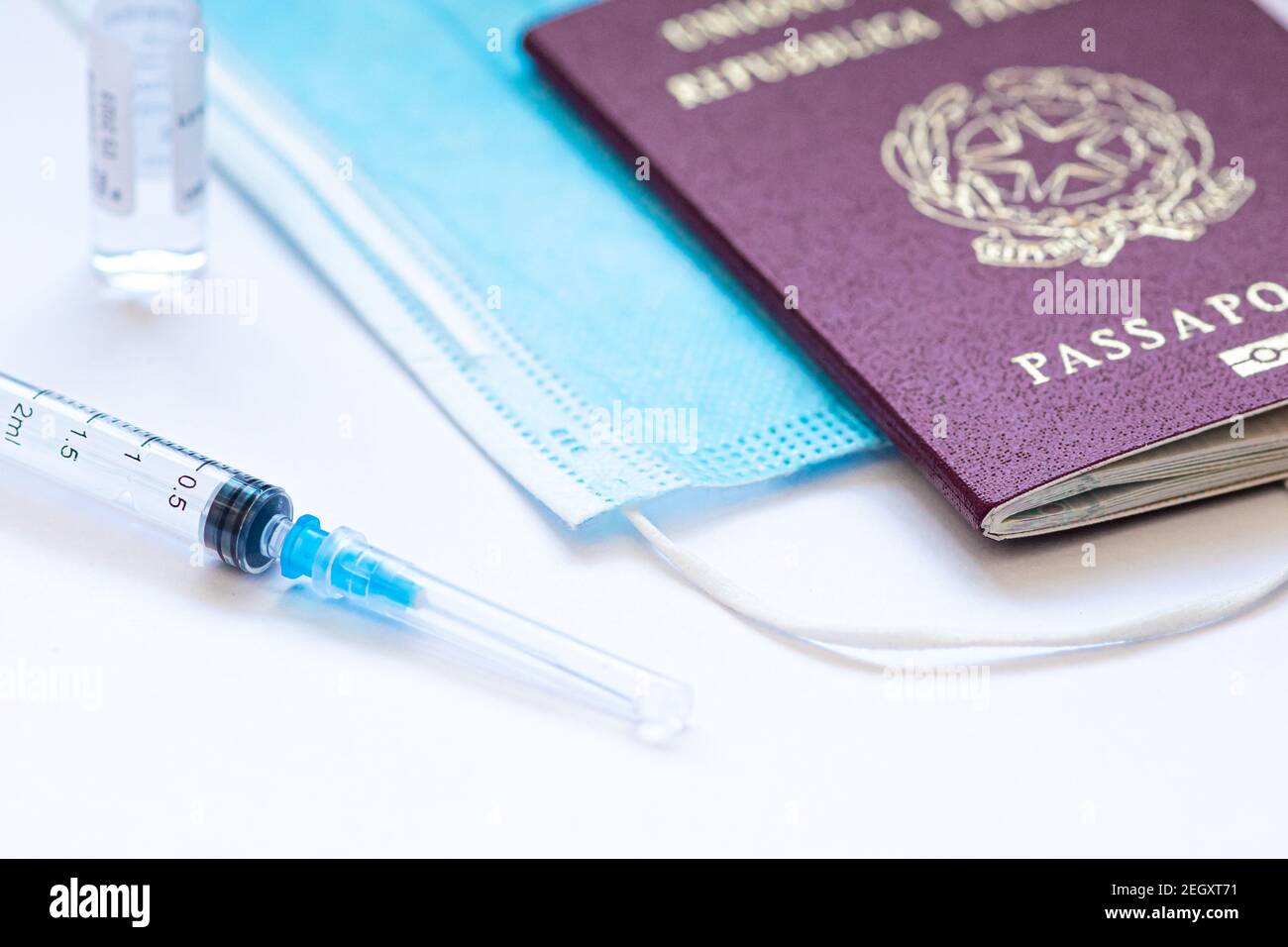 Syringe with needle, vial, surgical face mask and passport or visa on a white table ready to be used. Covid or Coronavirus vaccine background Stock Photo