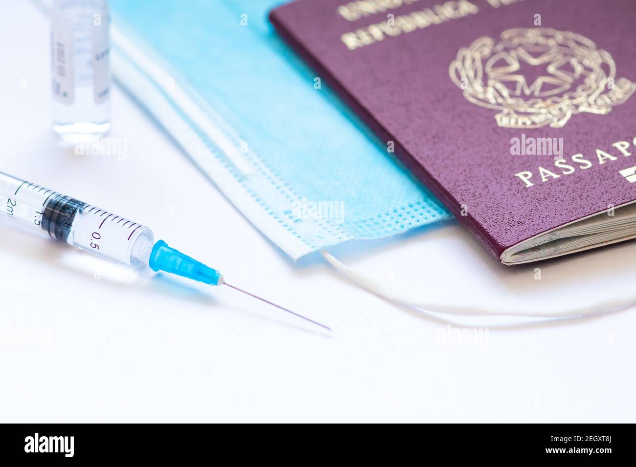 Syringe with needle, vial, surgical face mask and passport or visa on a white table ready to be used. Covid or Coronavirus vaccine background Stock Photo