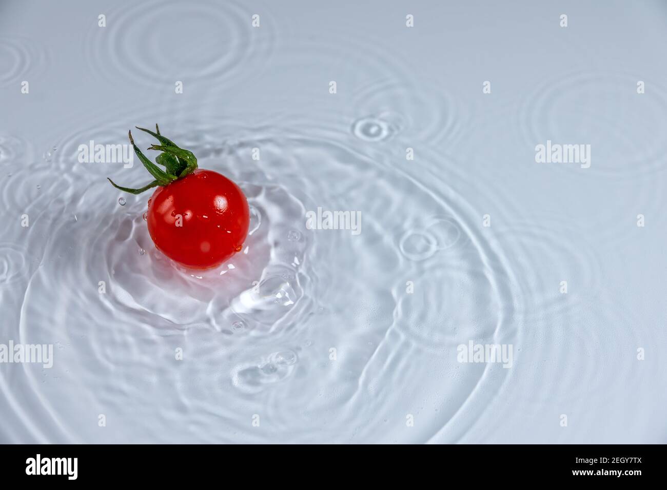 Juicy and ripe cherry tomato fall into the water Stock Photo