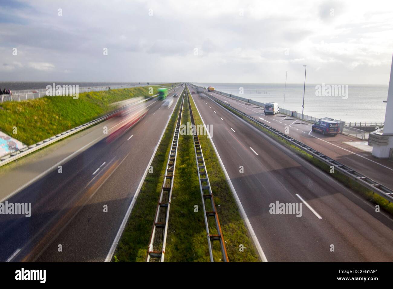 Motorway A7 on Afsluitdijk, a dam separating the North Sea from the Ijsselmeer lake. View from bridge at Breezanddijk, an artificial island created by Stock Photo