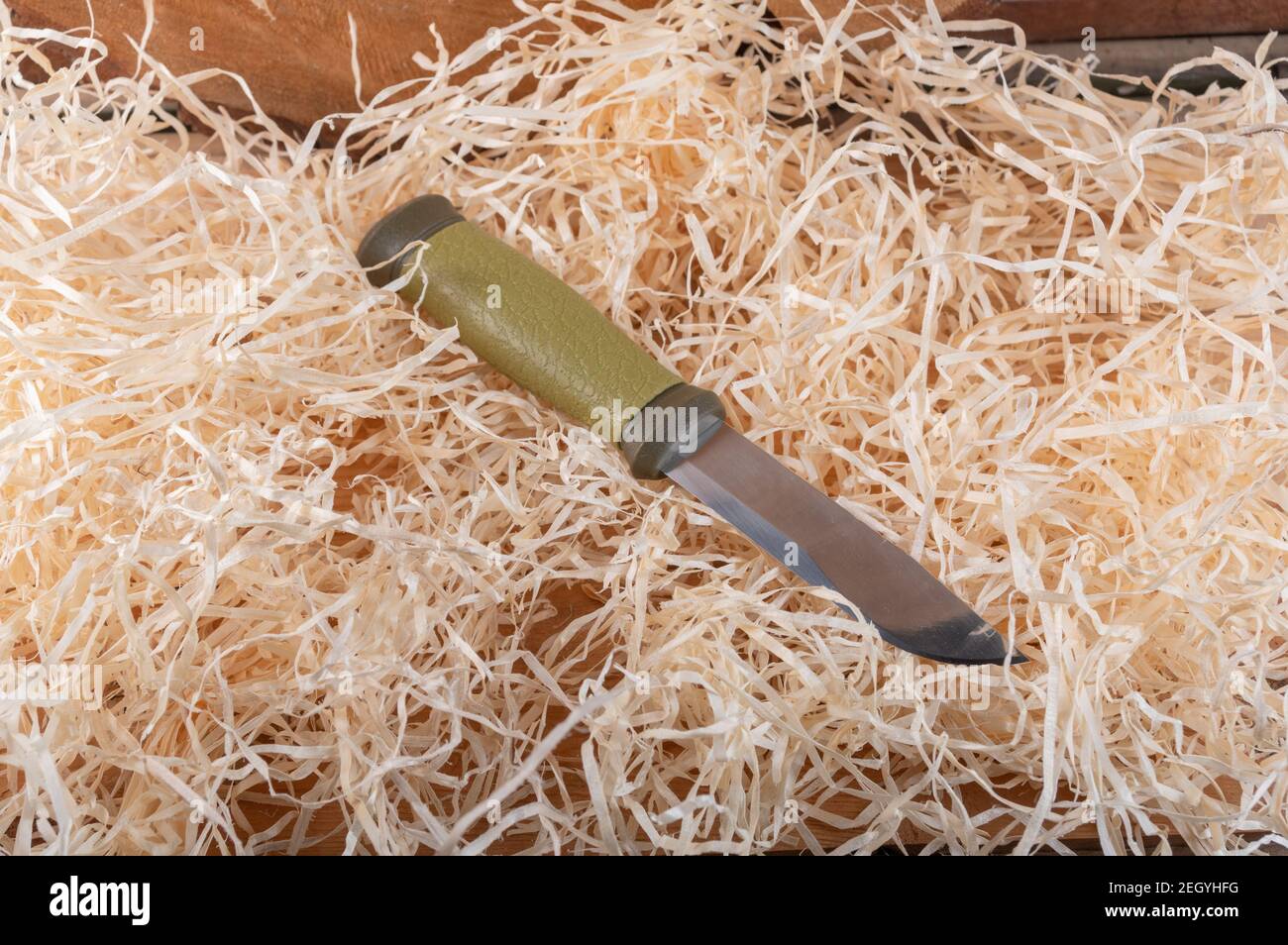 Tourist knife with a fixed blade in the hay. Knife lying in wood