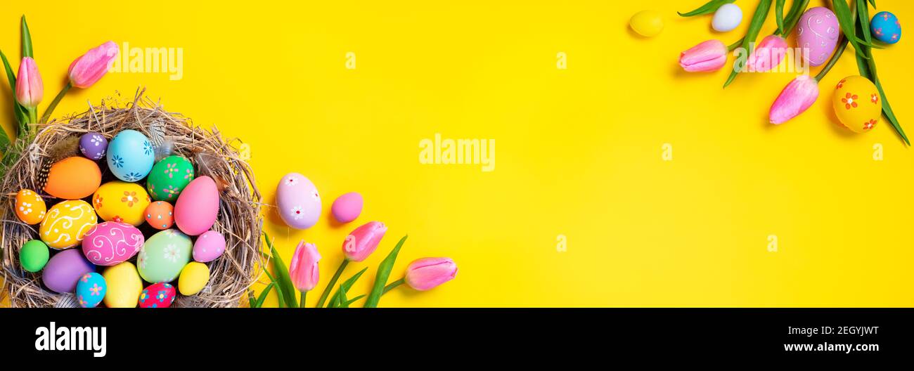 Easter - Decorated Eggs In Nest With Pink Tulips In Yellow Background Stock Photo