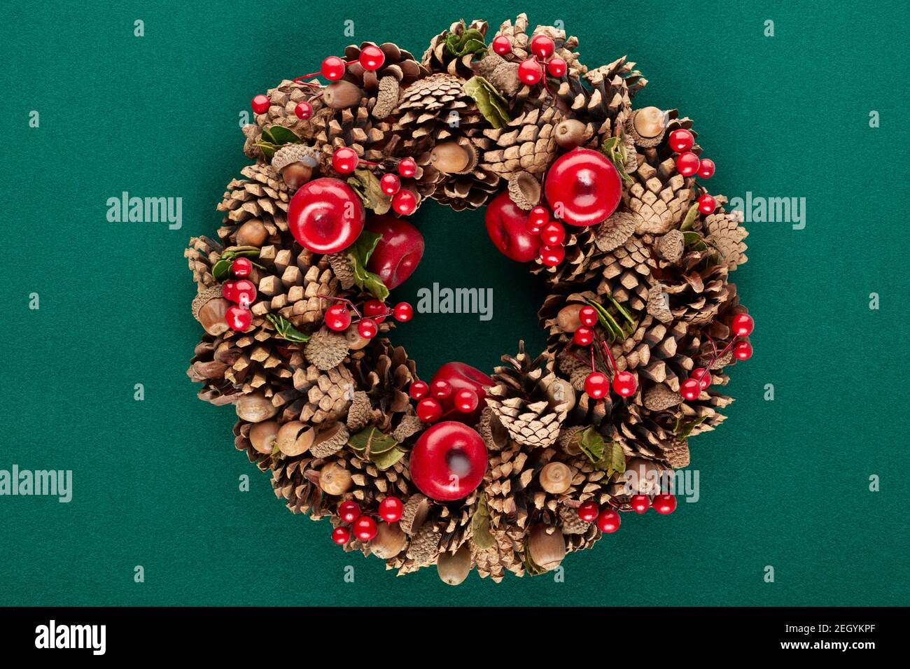 Christmas wreath with pine cones, red berries and acorns on green ...