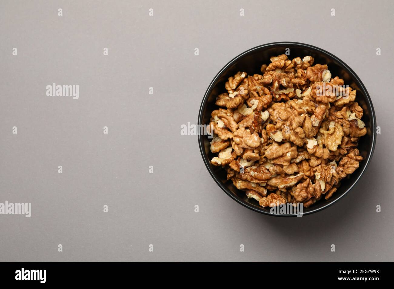 Bowl with tasty walnuts on gray background Stock Photo