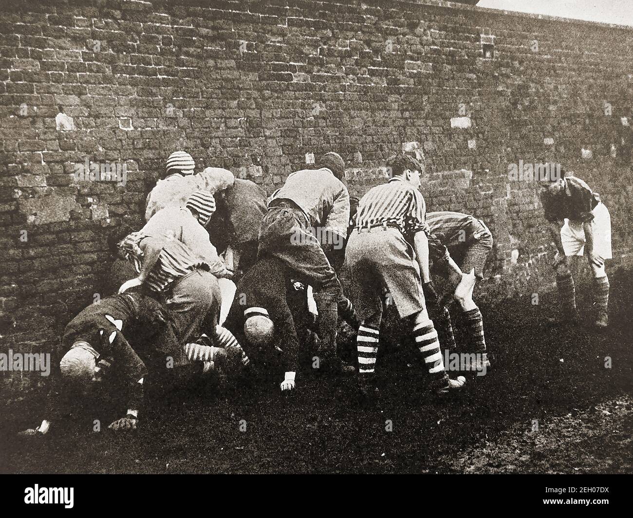 ETON UNIVERSARY, ENGLAND - An early printed photograph showing a 'bully' (Scrummage)  taking place during the annual  Eton Wall game on St Andrew's Day 1948. The Eton wall game  originated at and is still played at Eton College, played on a strip of ground 5  X 110 metres known as  The Furrow and against   a slightly curved brick wall that was built in 1717 Stock Photo