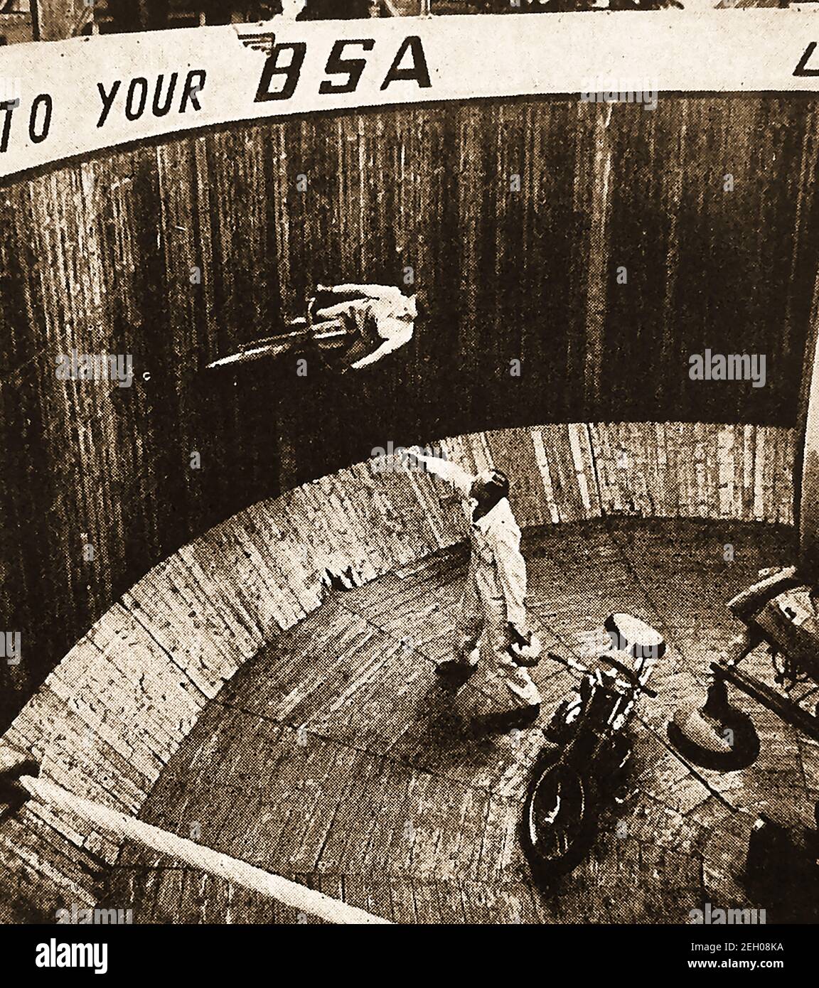 An early printed photograph showing motorcyclist performing on the Wall of Death at the Kursall, Southend, England. The Kursaal is a Grade II listed building  noted for its architectual style and  domed top in Southend-on-Sea, Essex, England.  It opened in 1901 as part of one of the world's first purpose-built amusement parks. The wall of death (sometimes known as The wall of death, motordrome, silodrome or well of death  is a wooden planked barrel shaped arena where spectators watch from the top as  motorcycles or other motorised  vehicles ride aroun it at speed,often performing other stunts. Stock Photo