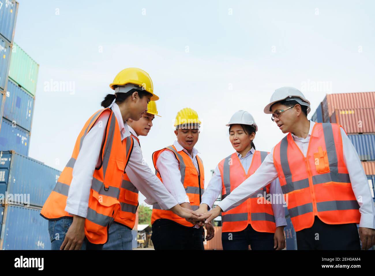 Asian foreman and his team worker standing hands holding together at the container depot terminal for unity and success concept. Stock Photo