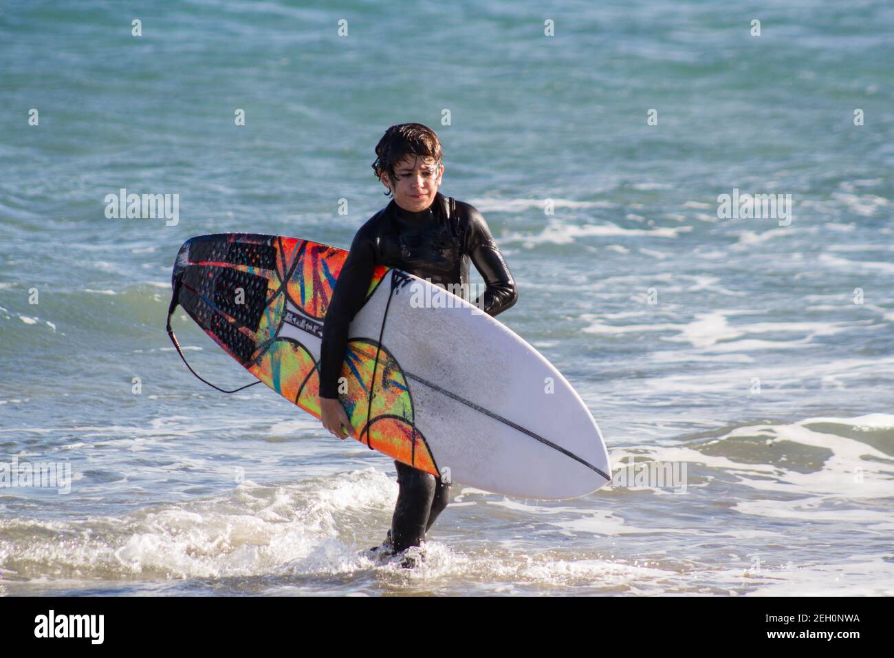 A boy, with its surfboard, is evaluating the surf Stock Photo - Alamy