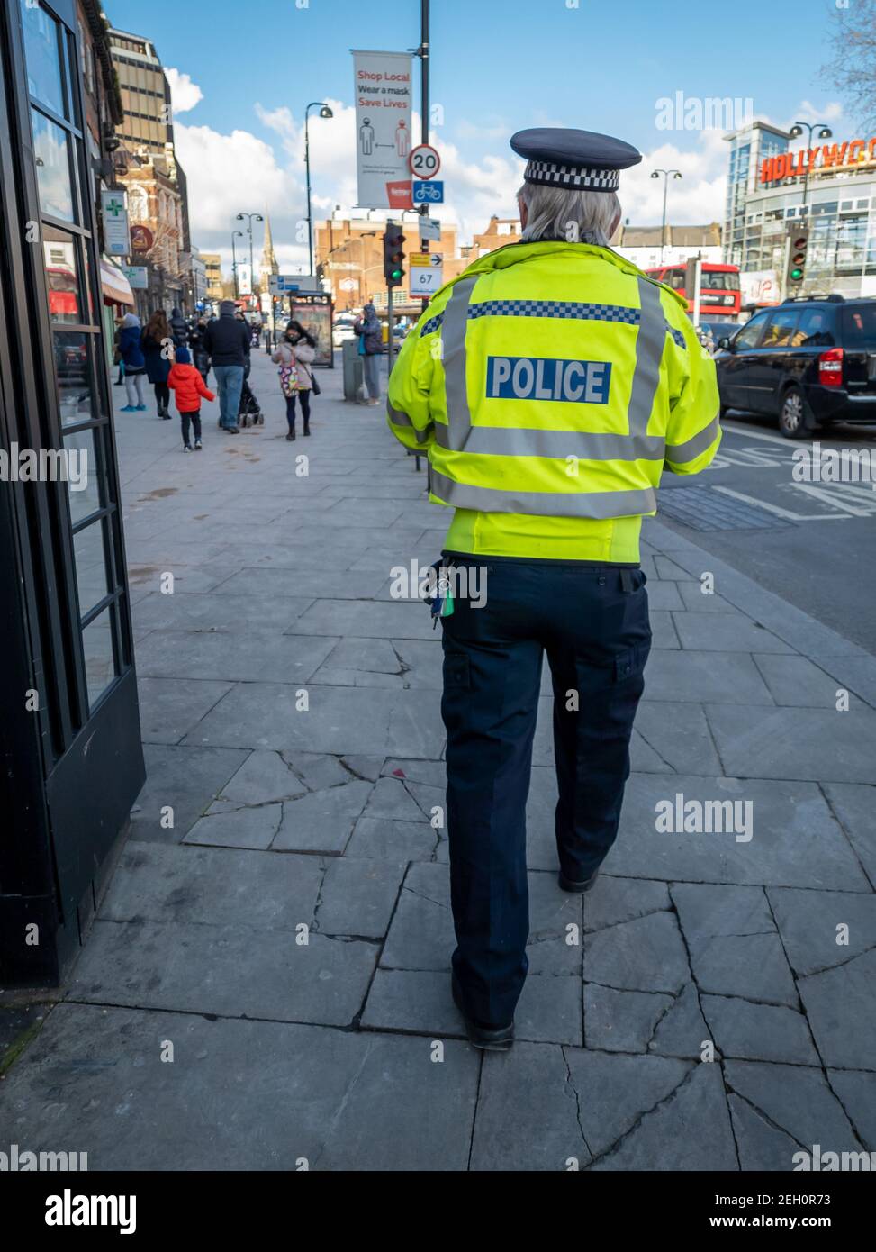 A police officer patrolling the high street to enforce Covid-19 national lockdown regulations. Stock Photo