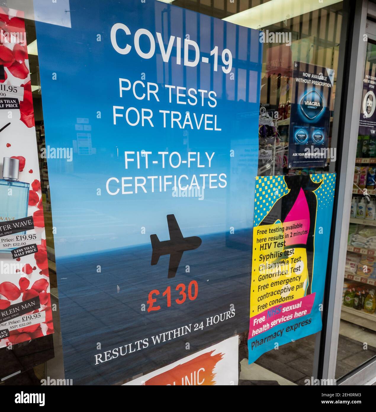 A poster in the window of a pharmacy offering commercial Covid-19 PCR test for travel. Stock Photo