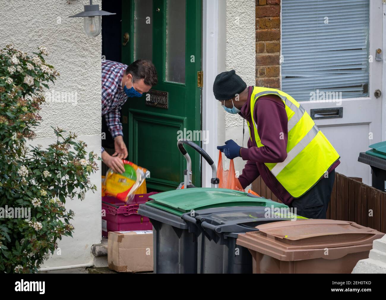 A driver delivery man working for a supermarket making a online grocery home delivery to a customer. Stock Photo