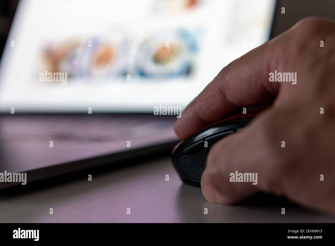 A person using a laptop computer doing online grocery shopping for home delivery. Stock Photo