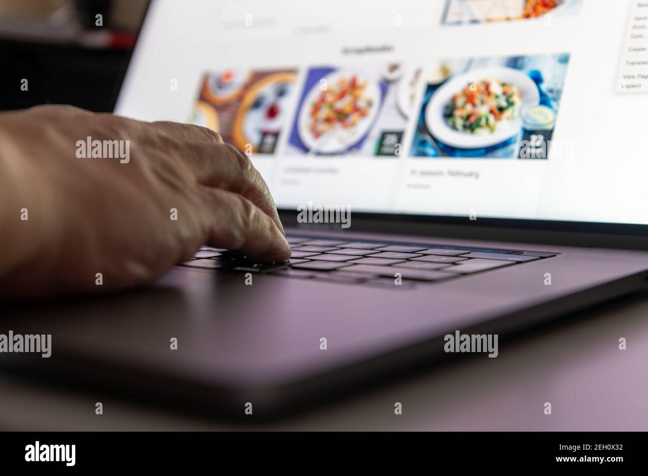 A person using a laptop computer doing online grocery shopping for home delivery. Stock Photo