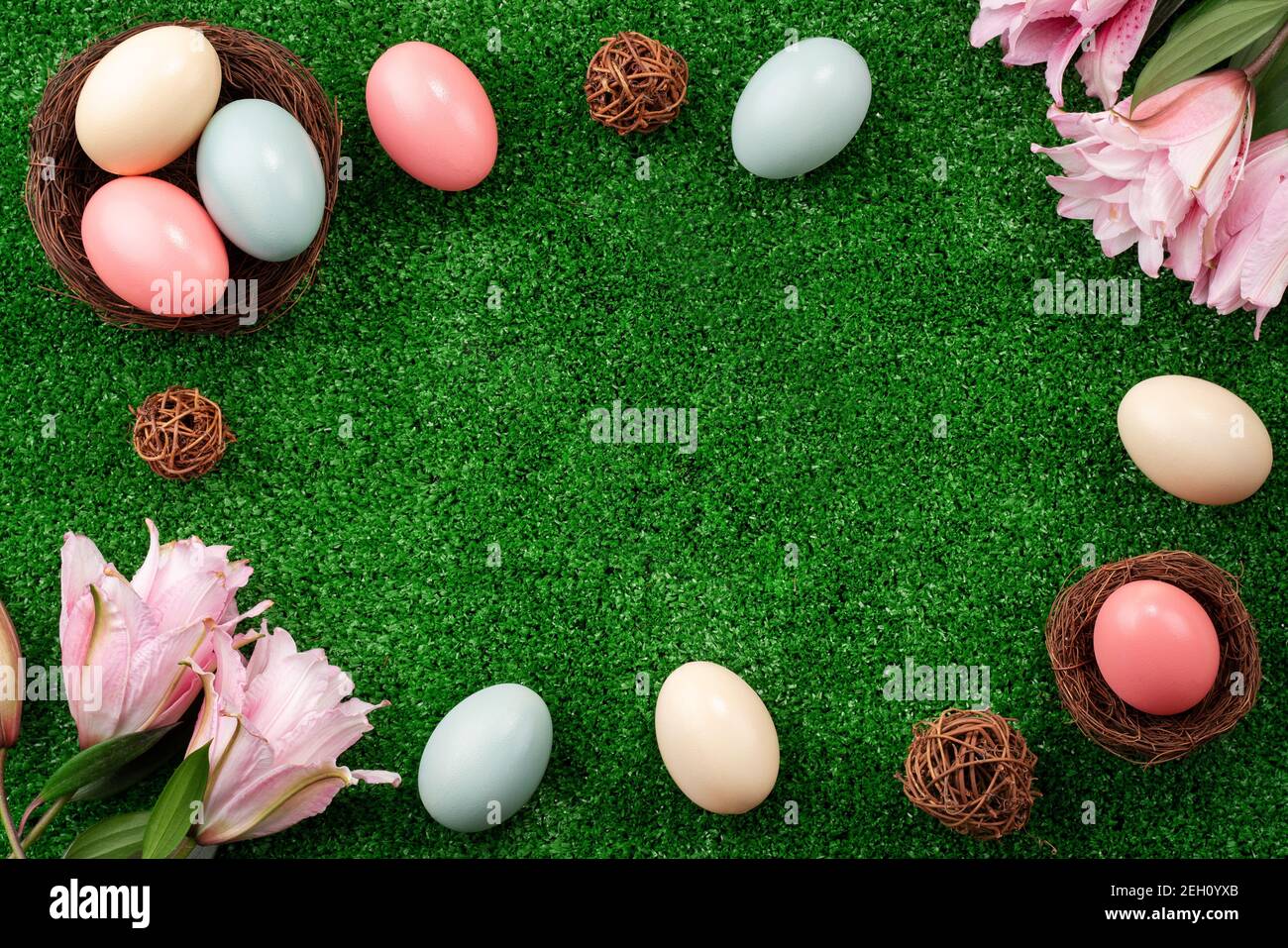 Colorful Easter eggs in the nest with pink lily flower on a lawn grass ...