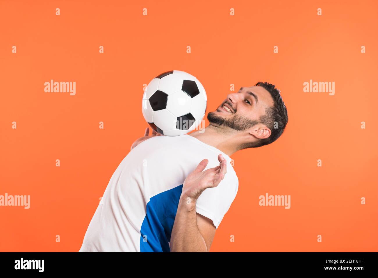 Smiling Soccer player trap a ball with his chest, isolated on orange  background Stock Photo - Alamy