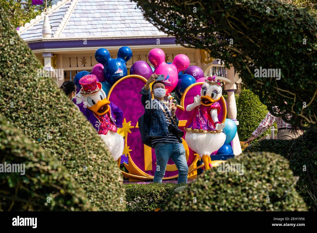 A visitor takes a selfie while maintaining social distance with the actors dressed as the Disney cartoon characters of Donald Duck and Daisy Duck during the reopening of the Hong Kong Disneyland Resort.The Hong Kong Disneyland Resort reopens its door to visors as the city's government has relaxed the lockdown restrictions as the infection rate of the Covid-19 coronavirus has reduced significantly in recent days. Stock Photo