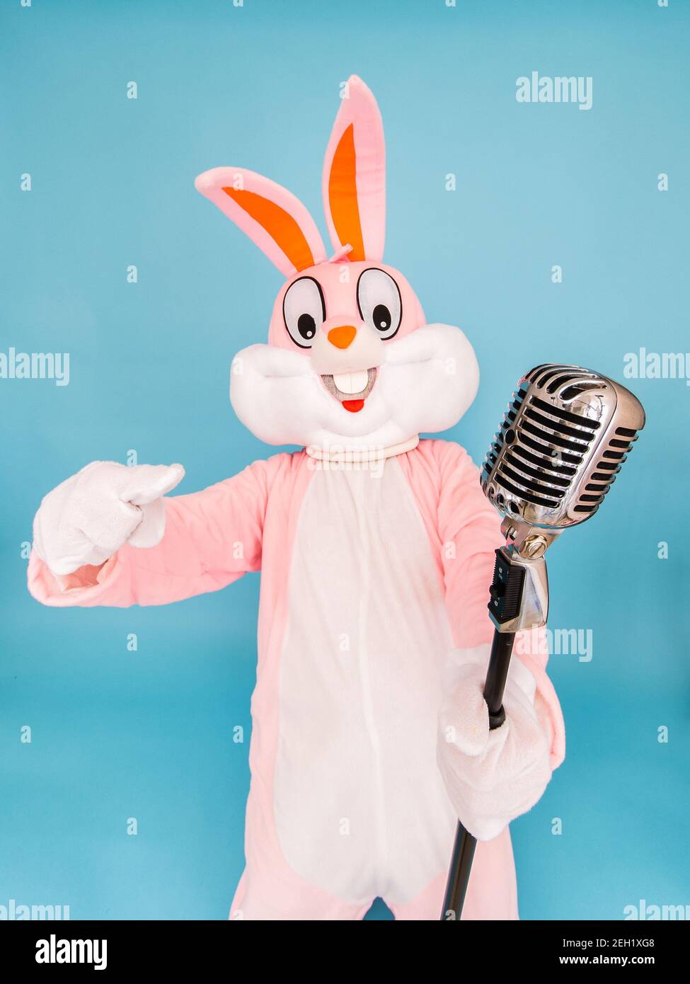 Positive funny man or kid singer or vocalist sings song to retro vintage classic microphone. Easter bunny or rabbit or hare celebrates Happy easter Stock Photo