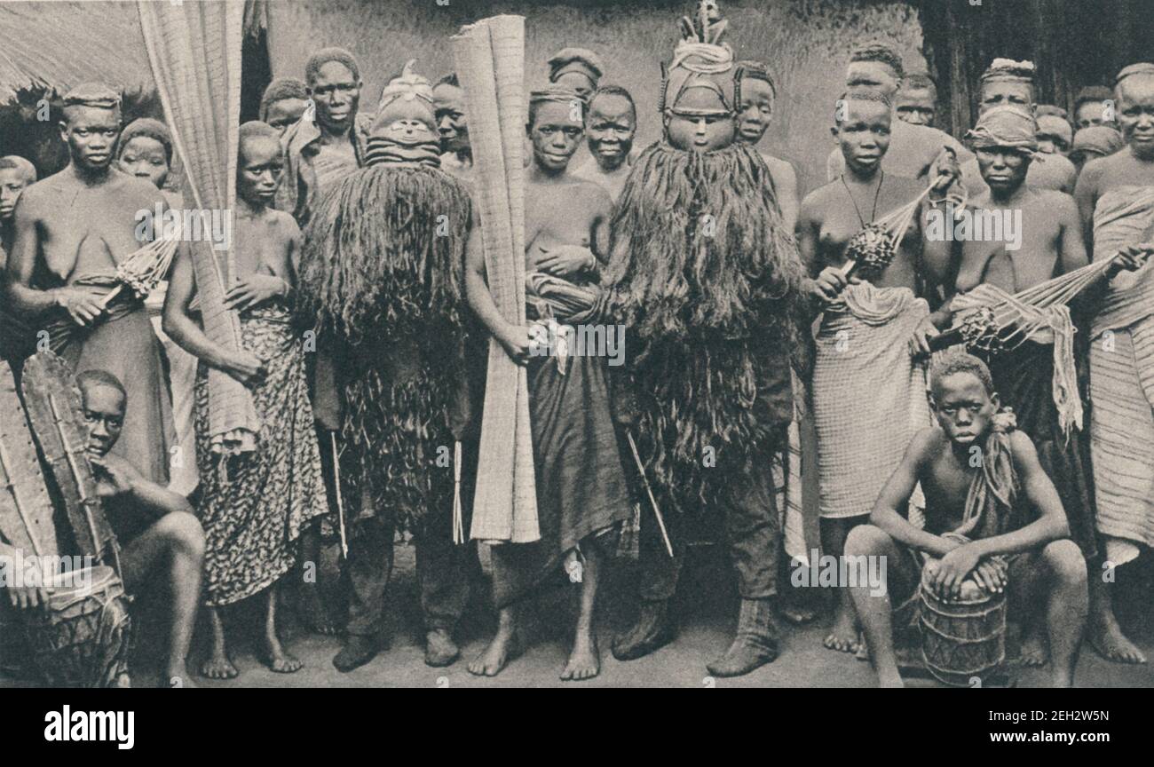 An early 20th century photo of a group of women partaking in Sande a women's initiation society in Sierra Leone. The Sande society initiates girls into adulthood by rituals including female circumcision. Some members are wearing masks or ndoli jowei Stock Photo