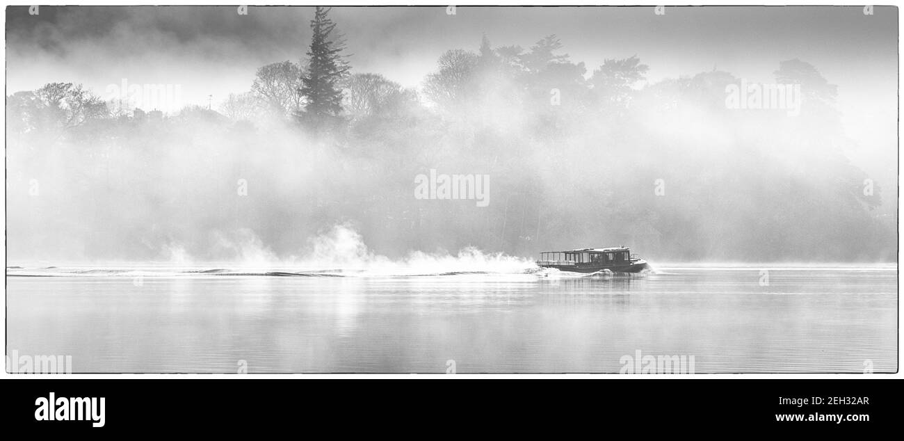 Early morning ferry on lake in mist Stock Photo