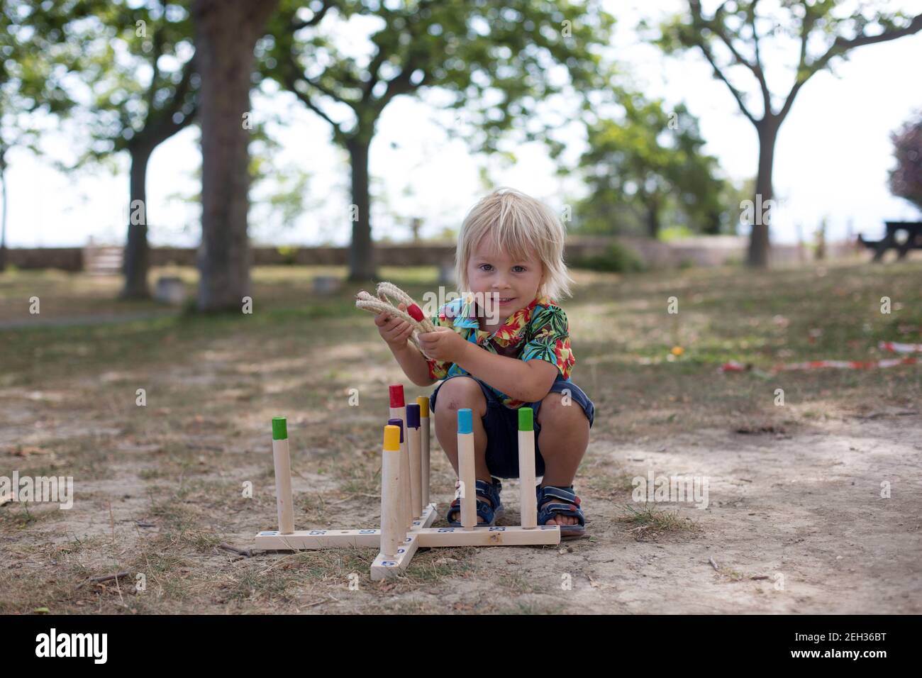 Child, boy, playing game with hoops and rings, throwing and trying to strike a point, summertime