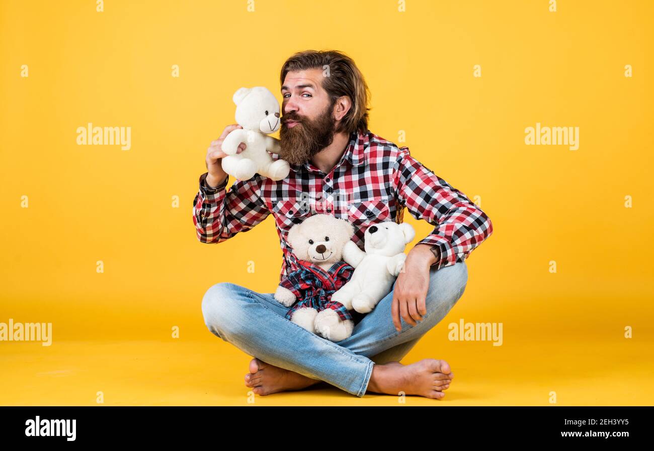 kiss of love. cheerful bearded man kissing teddy bear. male feel playful with bear. brutal mature hipster man play with toy. happy birthday. being in good mood. happy valentines day. Stock Photo