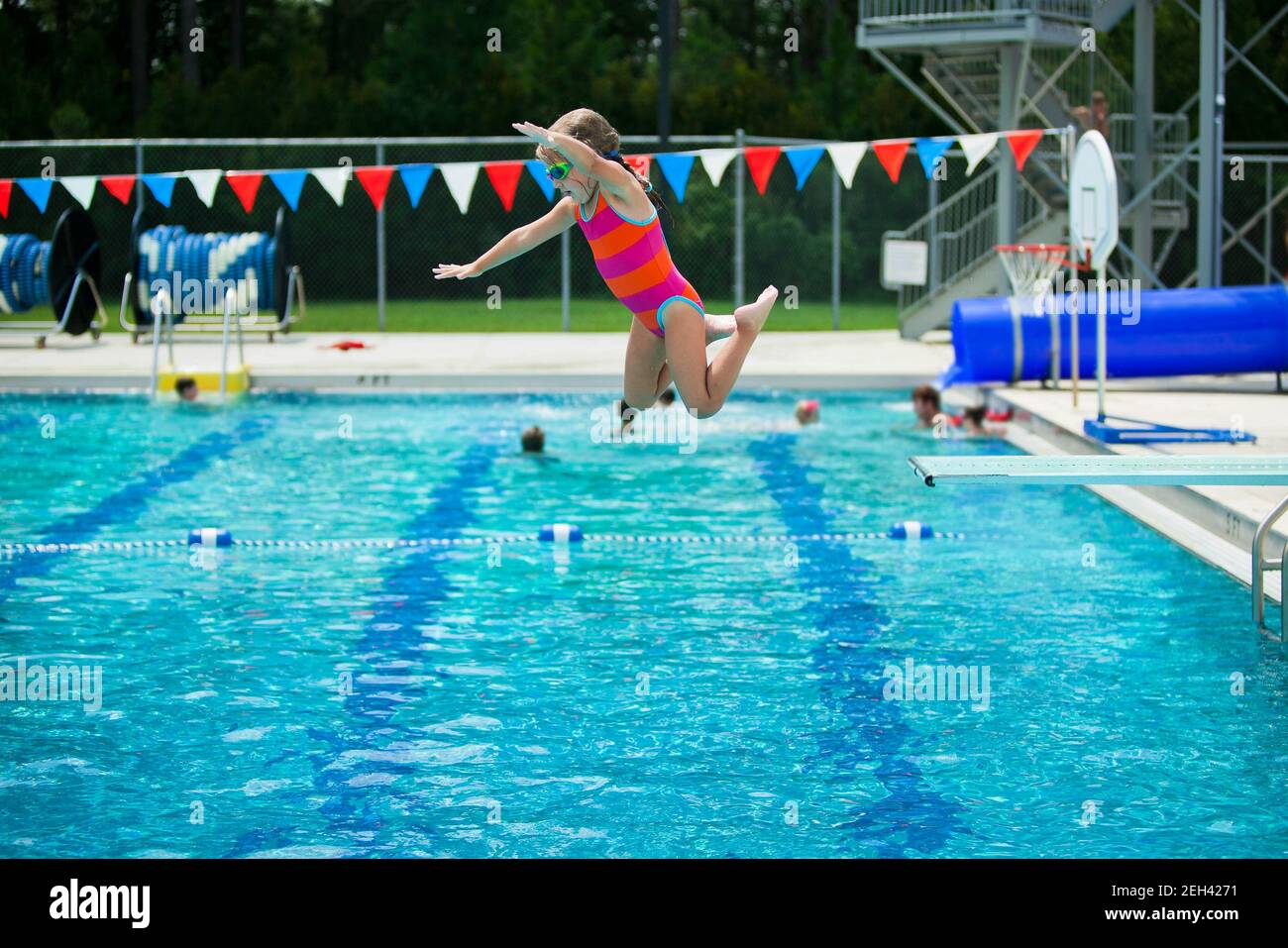 Little girl jumping off the diving board during her swim lessons at the