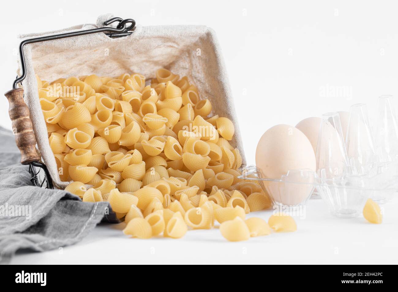 Basket of dry pasta and eggs on white background Stock Photo Alamy