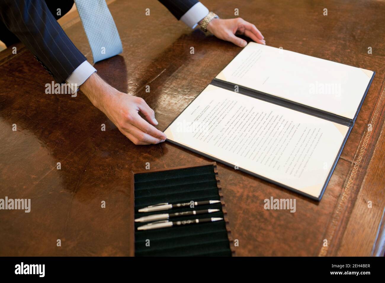 A staff member positions the Council of Environoment Quality (CEQ) Executive Order on President Barack Obama's desk prior to his signing the document in the Oval Office, Oct. 5, 2009. Stock Photo