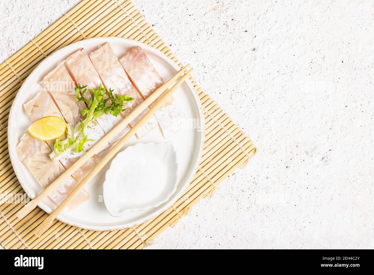 Pieces of raw hake. Fresh fish, lemon wedge, herbs, sea salt. Sashimi