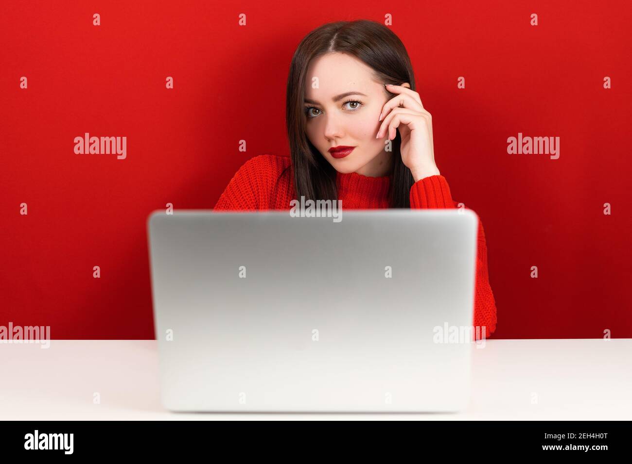 beautiful girl at the computer on a red background Stock Photo - Alamy