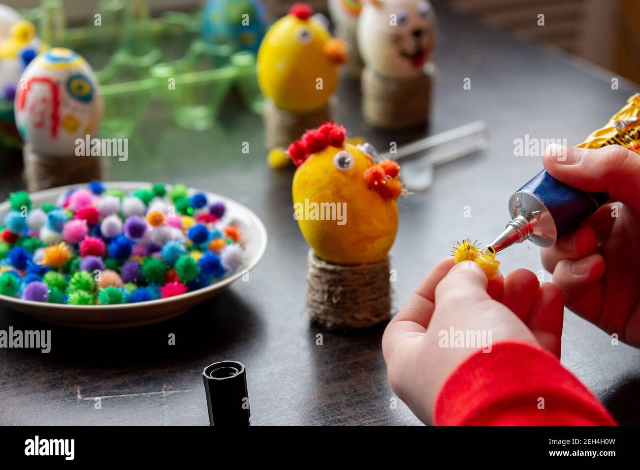 Children's hands apply glue to the egg craft element Stock Photo