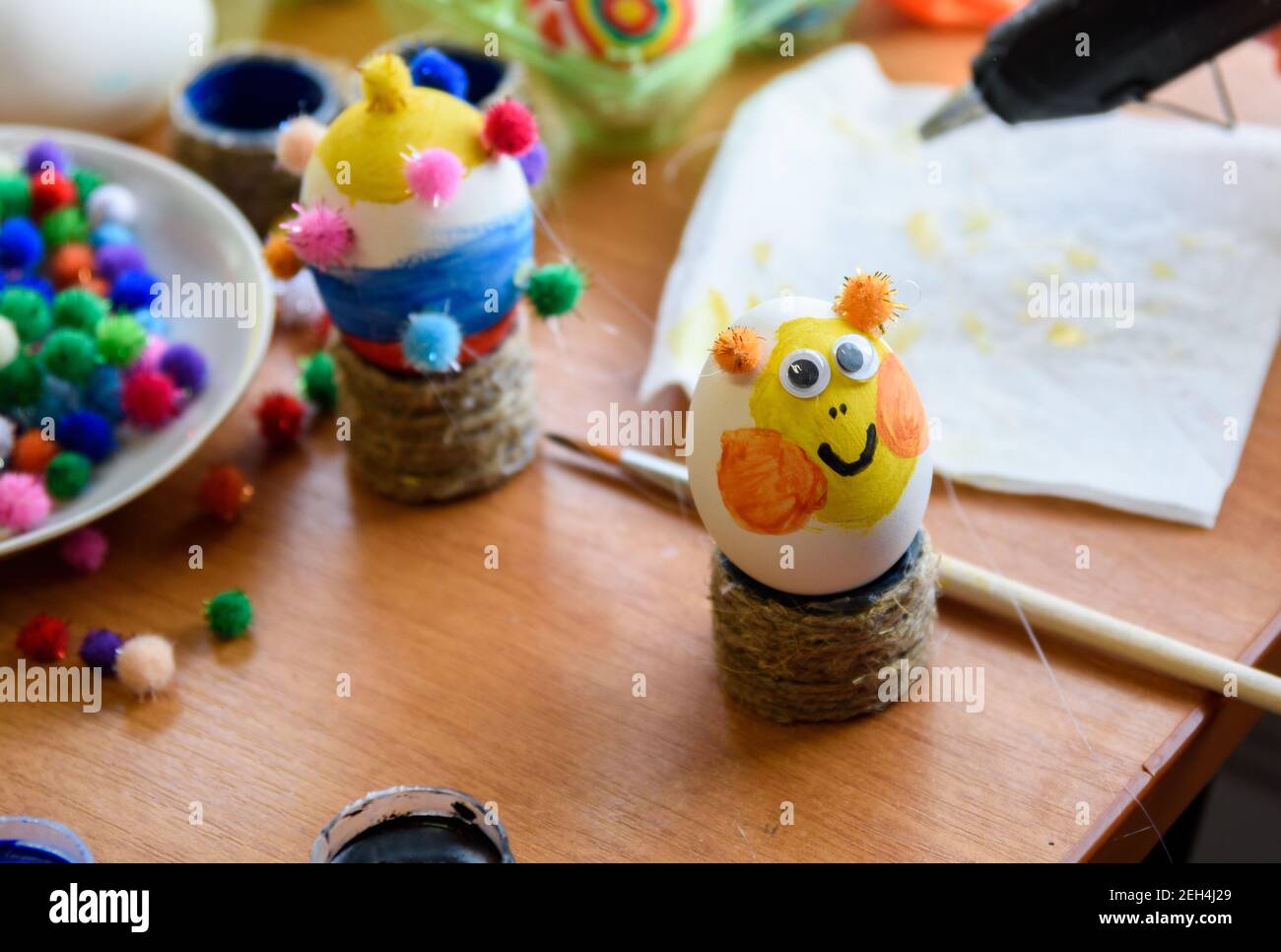Painted easter egg with glued eyes stands on the table Stock Photo