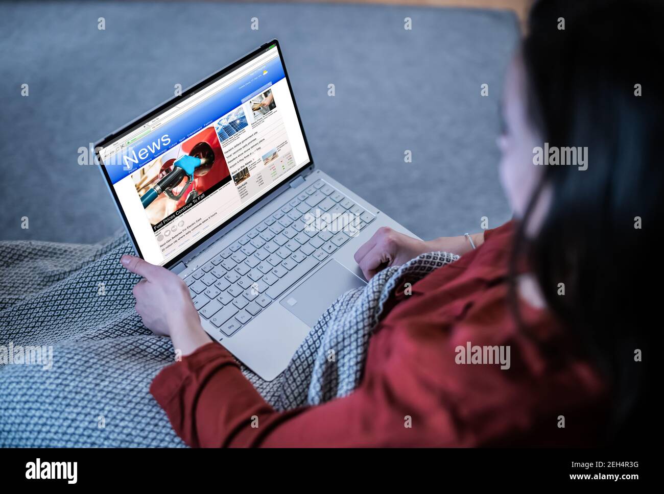 Watching News Articles On Laptop Online At Night Stock Photo