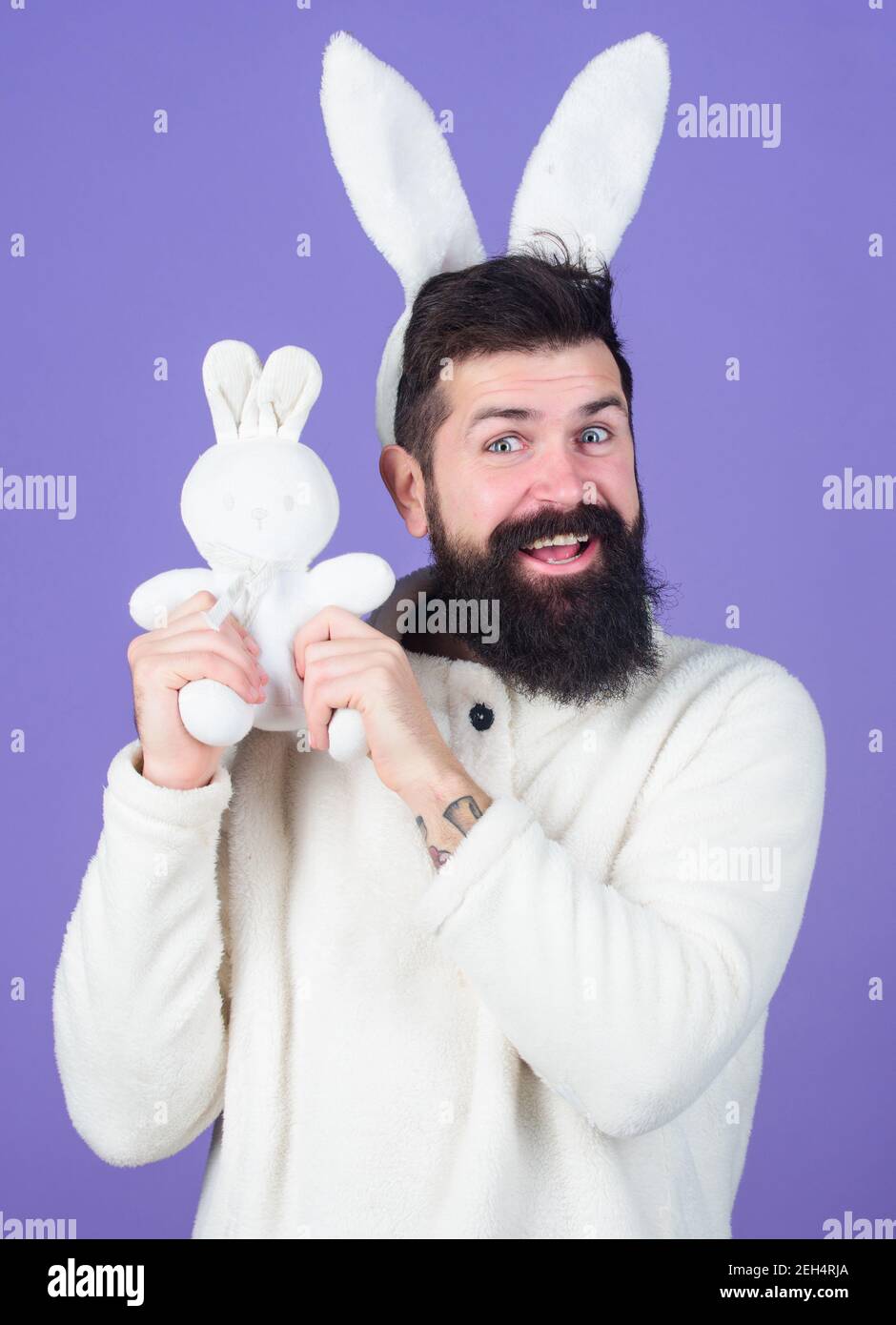 Having his own bunny. Happy man with rabbit ears kissing bunny toy ...