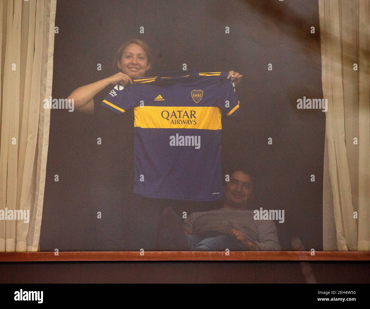 London, UK. 19th Feb, 2021. A woman holds up a Boca Juniors football shirt, sponsored by Qatar Airways. People in 10 day quarantine at the Radisson Blue Edwardian Hotel. People are flying via Heathrow, but the new quarantine restrictions for international travel from so called 'red list' countries means that the law requires quarantine in one of the Government approved hotels. National Lockdown 3 is in force with the Government instruction for everyone to stay at home. Credit: Mark Thomas/Alamy Live News Stock Photo