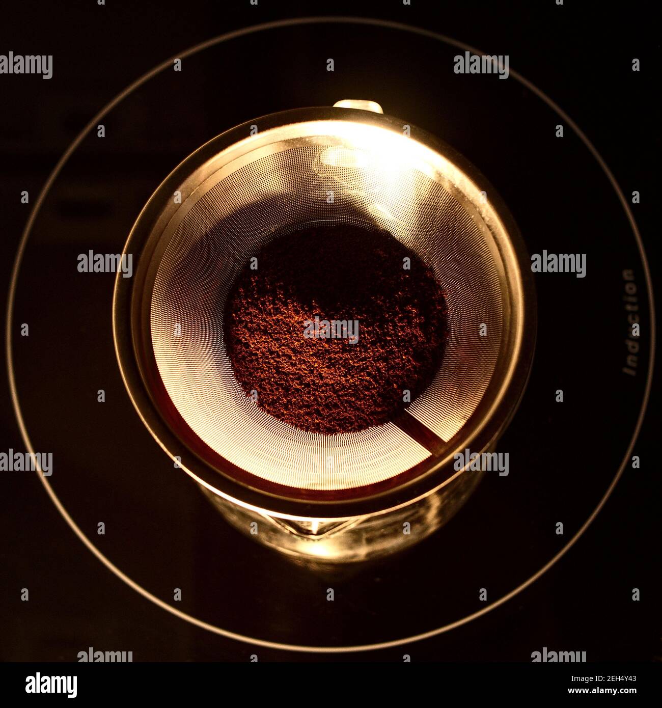 Coffee powder in a metal shiny coffee filter on a glass jug shot from