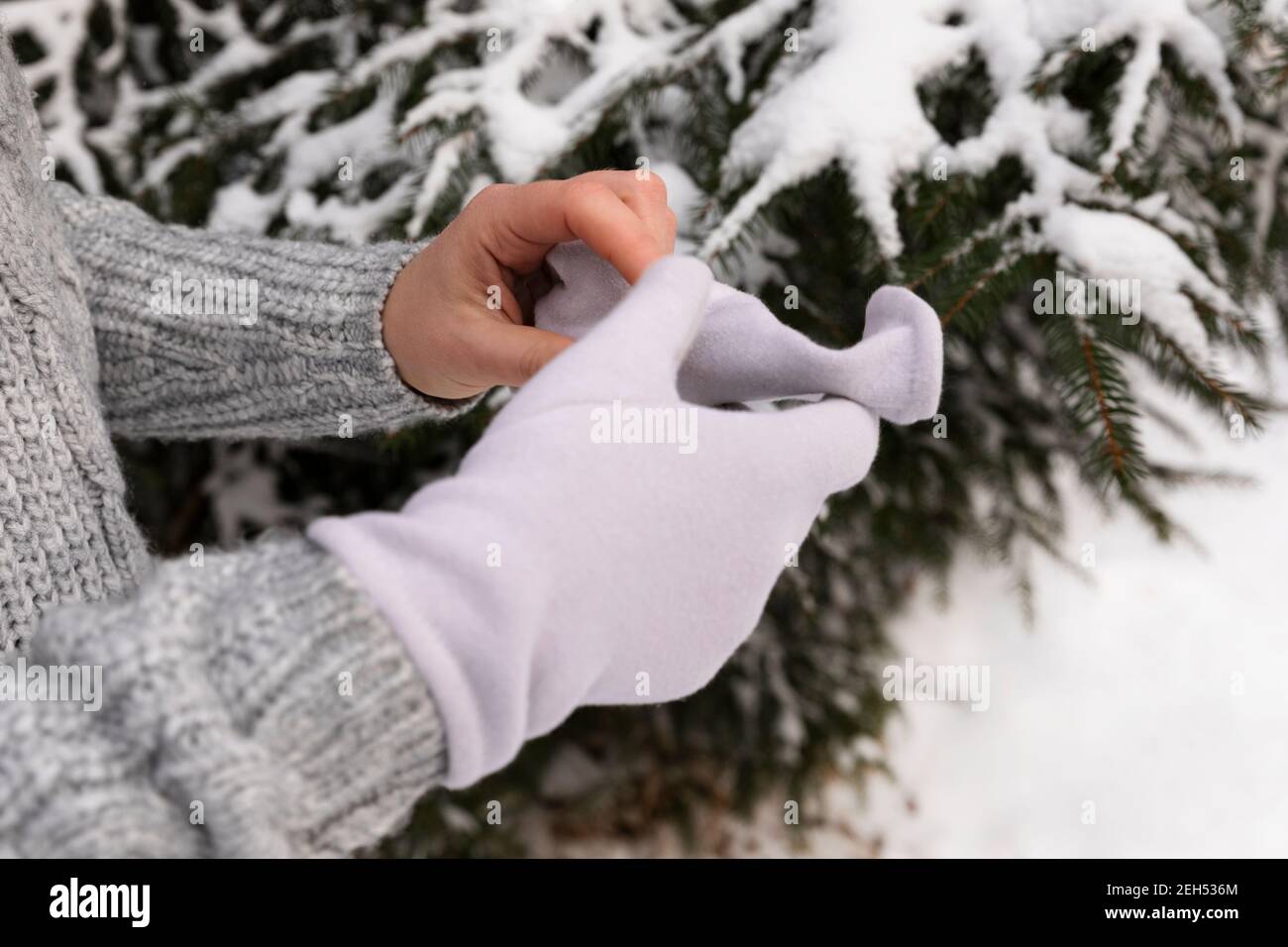 The woman puts on gloves as it is very cold outside. Frostbite of the