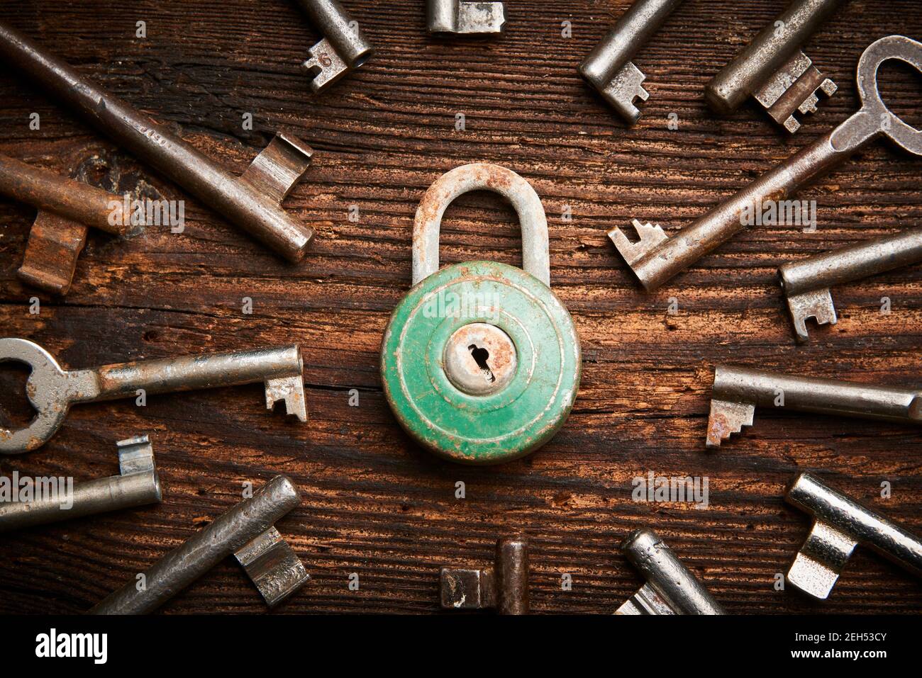 Vintage rusty padlock surrounded by group of old keys on a weathered wooden background. Internet security and data protection concept, blockchain and Stock Photo