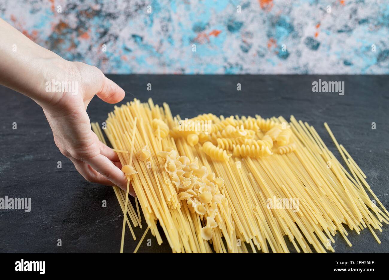 Female hands touching various pasta on dark surface Stock Photo
