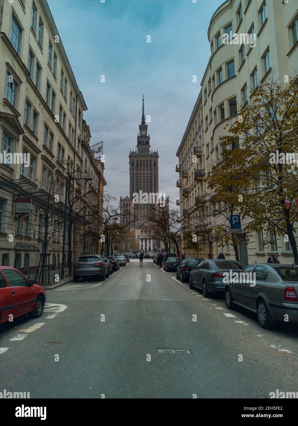Warsaw November 10 2019 Palace of Culture and Science at end of street and standing man between two long tenement houses Stock Photo