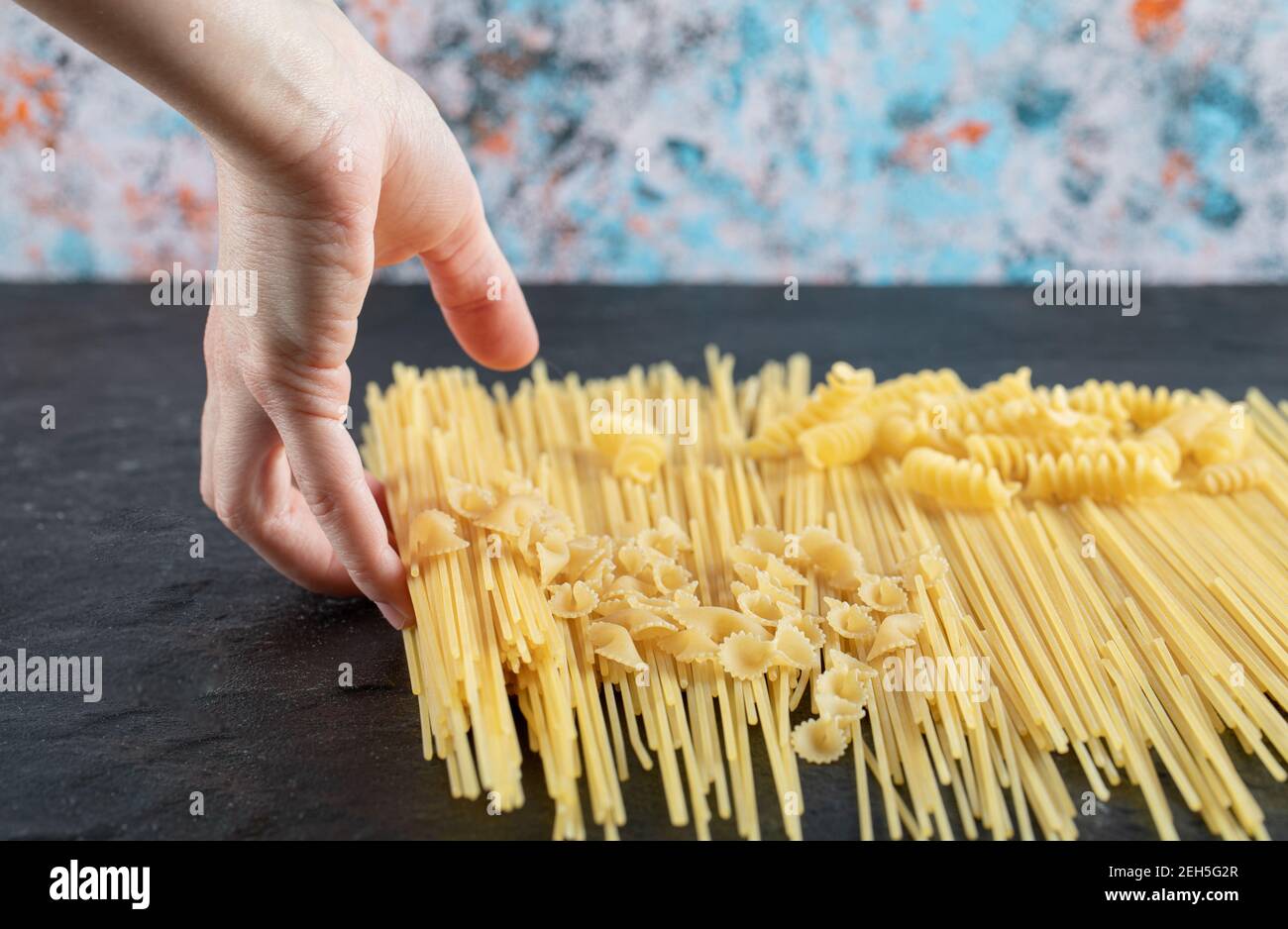 Female hands touching various pasta on dark surface Stock Photo