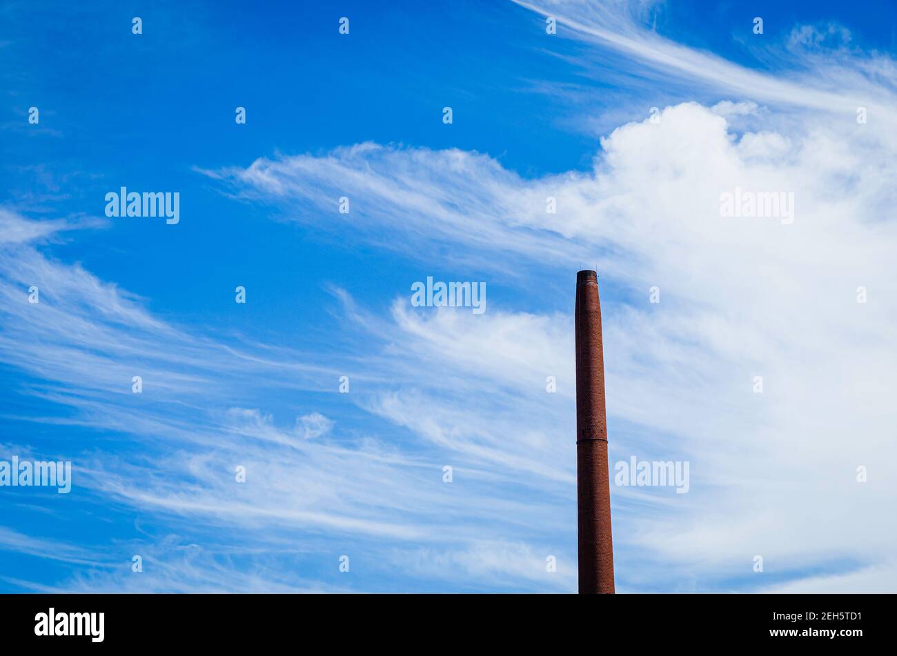 Smoke stack without smoke and a blue sky and some white clouds Stock Photo