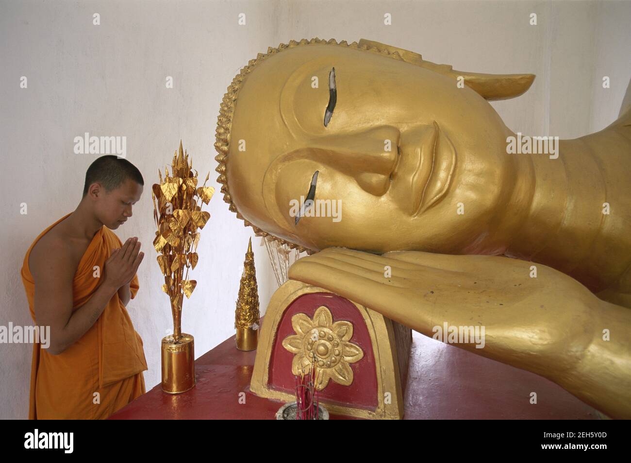Asia,Laos, Luang Prabang, Wat Saen temple, Buddhist Monk Praying to Reclining Buddha statue Stock Photo