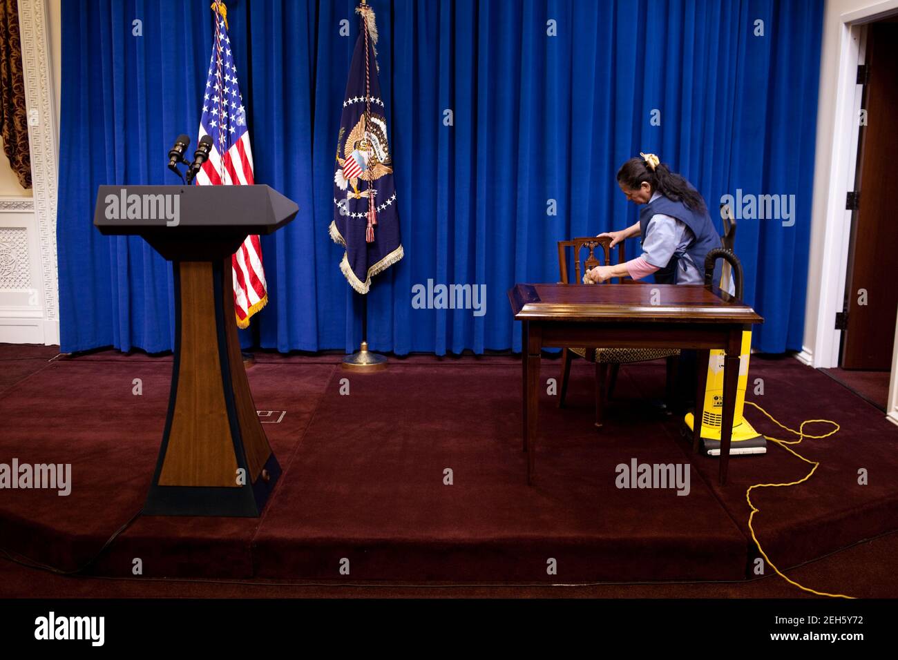 A custodian dusts and vacuums prior to President Barack Obama's Tax Deliquency Memorandum signing ceremony in the Eisenhower Executive Office Building of the White House,  Jan. 20, 2010. Stock Photo