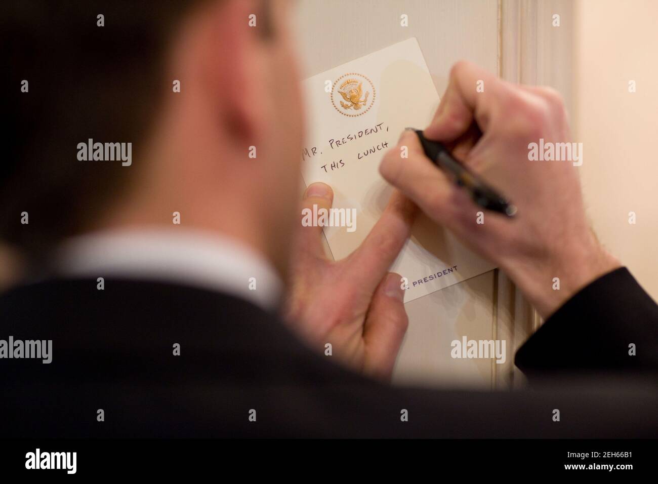Deputy Director of Oval Office Operations Brian Mosteller writes a note to President Barack Obama during his CEO lunch in the Old Family Dining Room of the White House, Feb. 4, 2010. Stock Photo