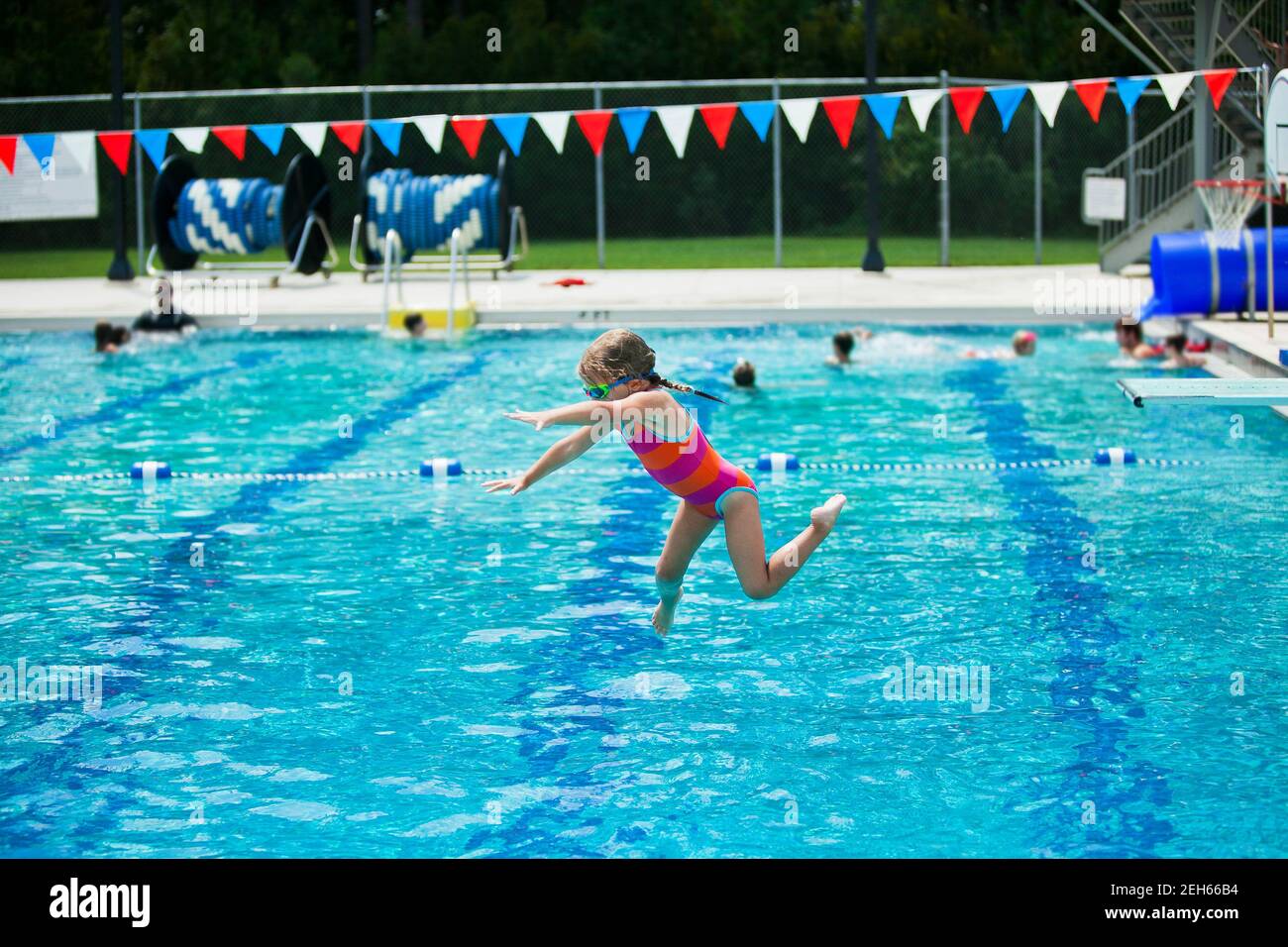 Little girl jumping off the diving board during her swim lessons at the