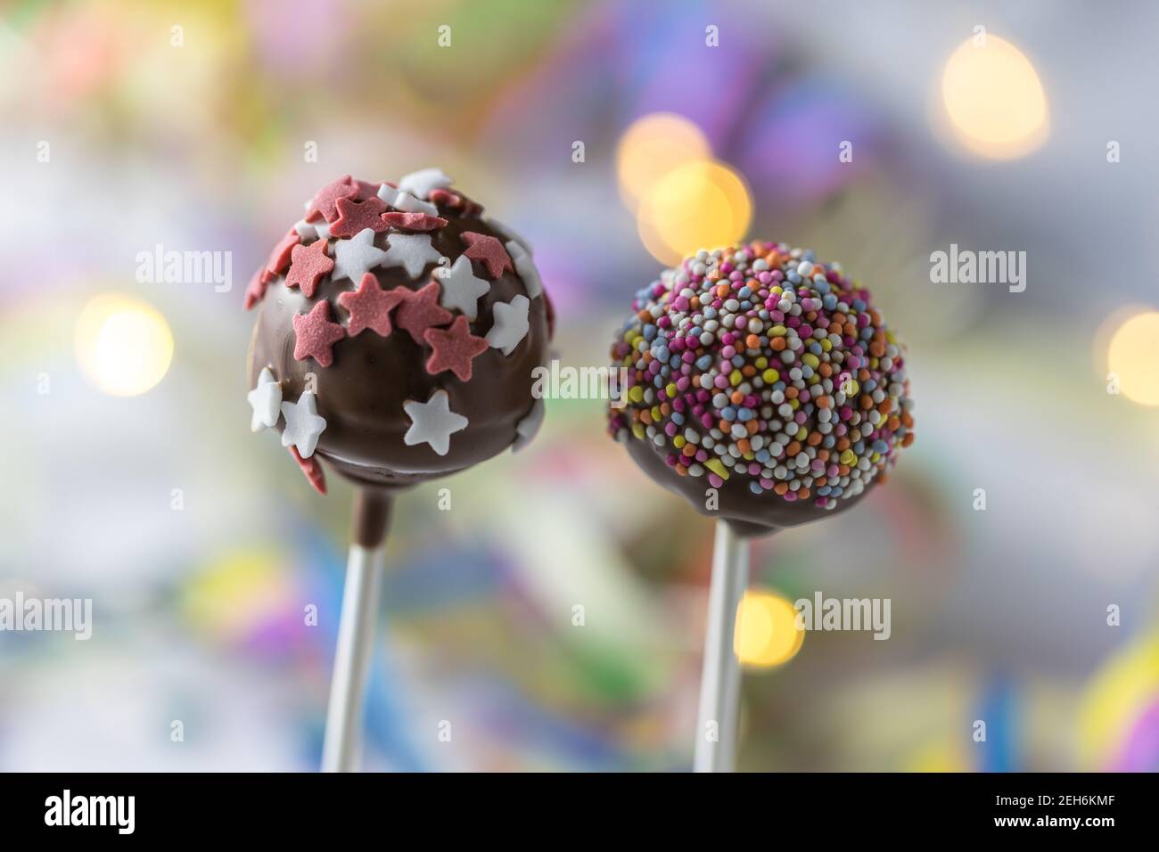 close up of two cake pops with chocolate and decoration with sugar in star shape, bokeh in the background Stock Photo