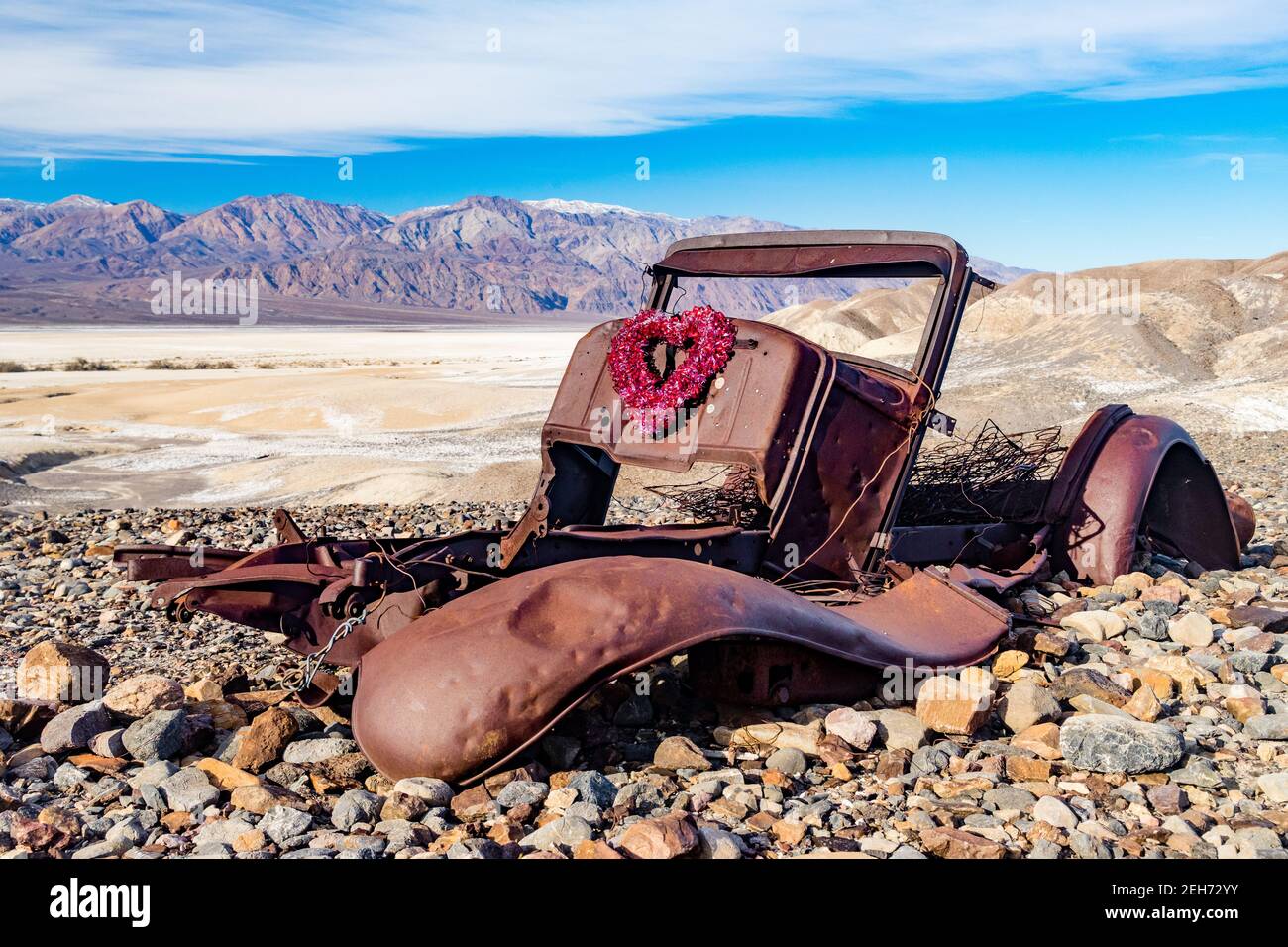 Rusty body of abandoned old car with valentine wreath attached in Death Valley National Park, California. Valentine Card concept Stock Photo