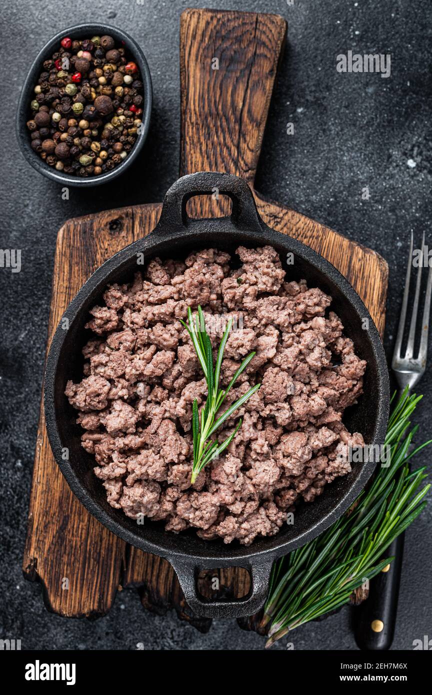 Fried mince beef meat in a pan for cooking pasta. Black background. Top